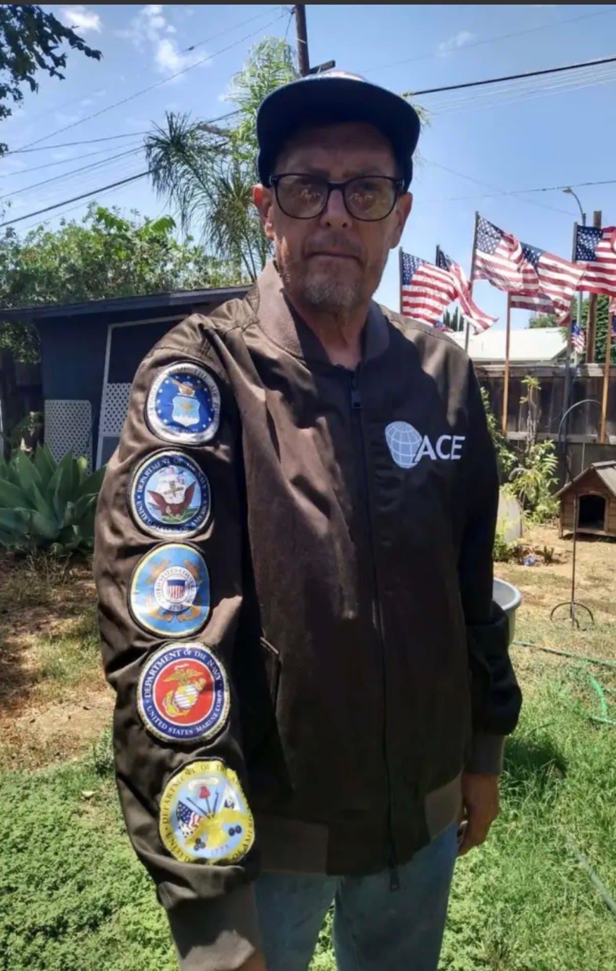 Kerry Sheron standing at home with U.S. flags in the background.